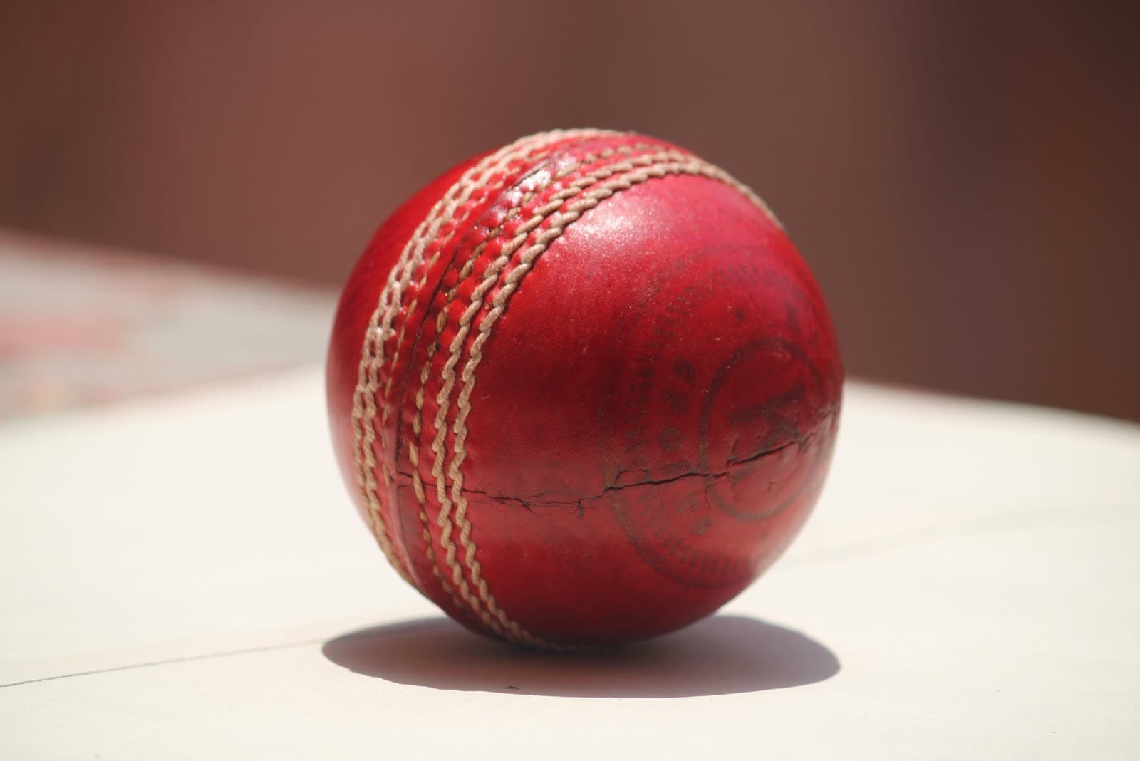 Close-up macro shot of a red leather cricket ball