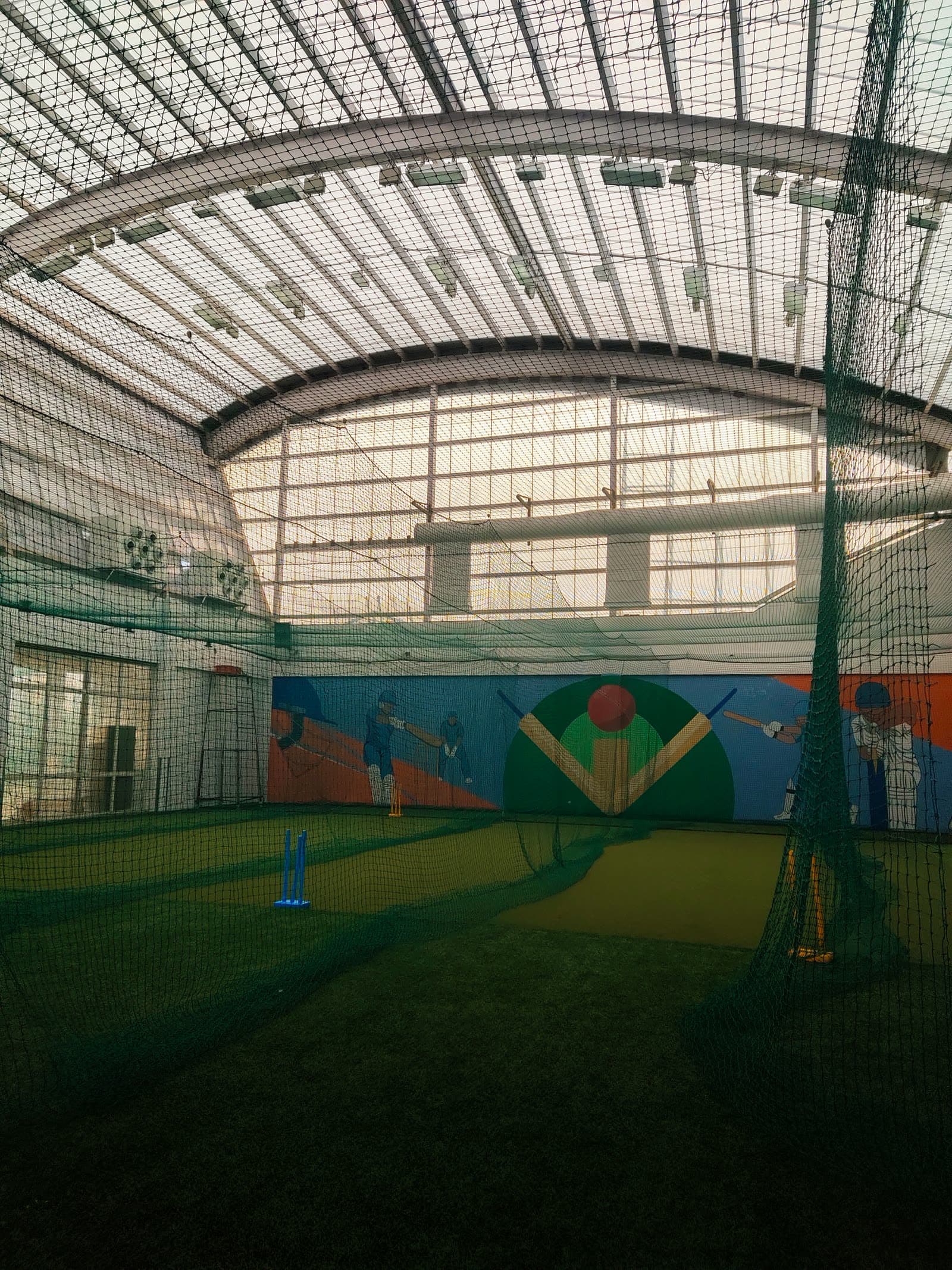 Indoor cricket net facility with artificial turf, stumps and netting under a covered dome