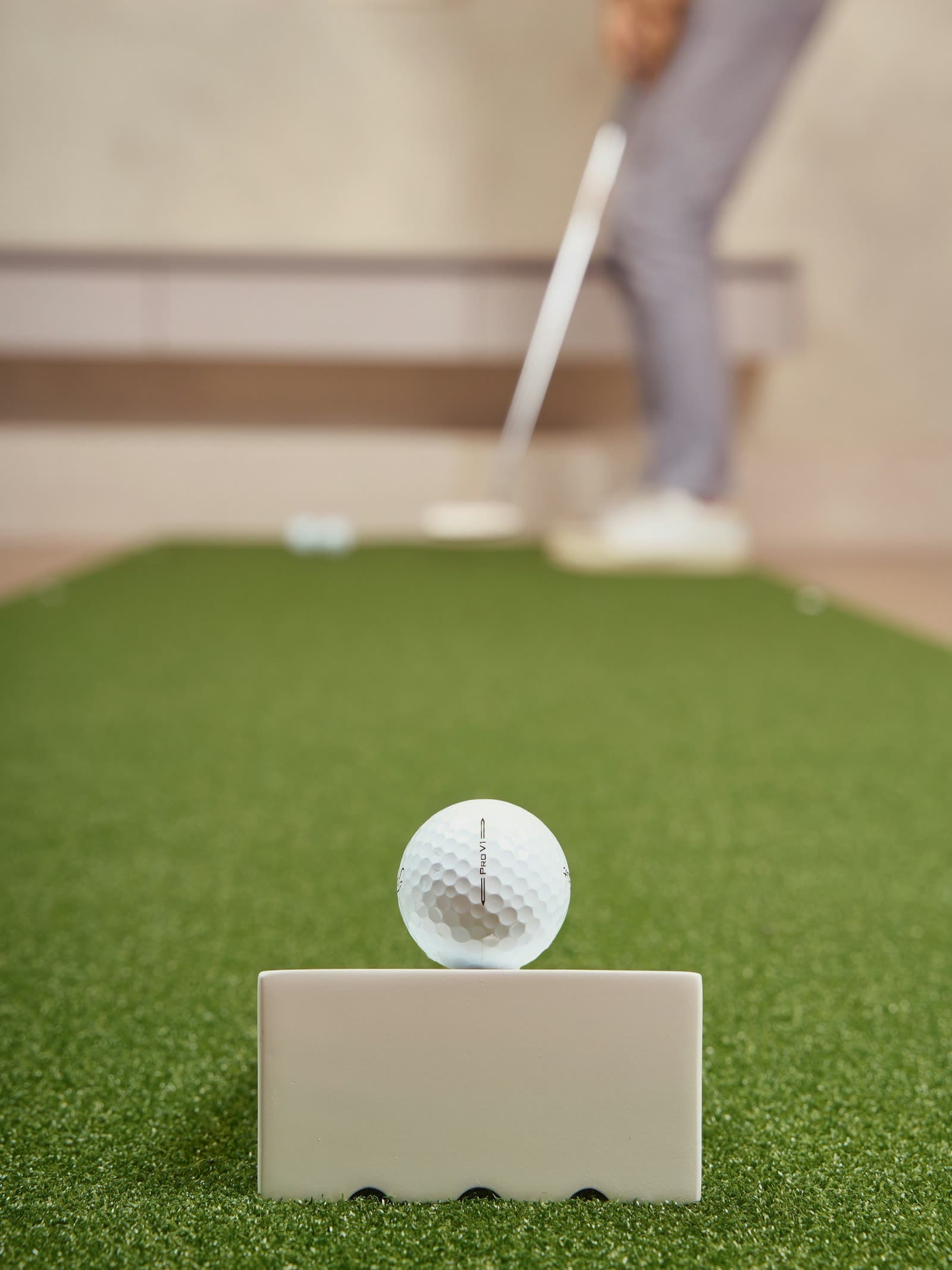 Golf ball resting on a tee inside an indoor putting and practice space