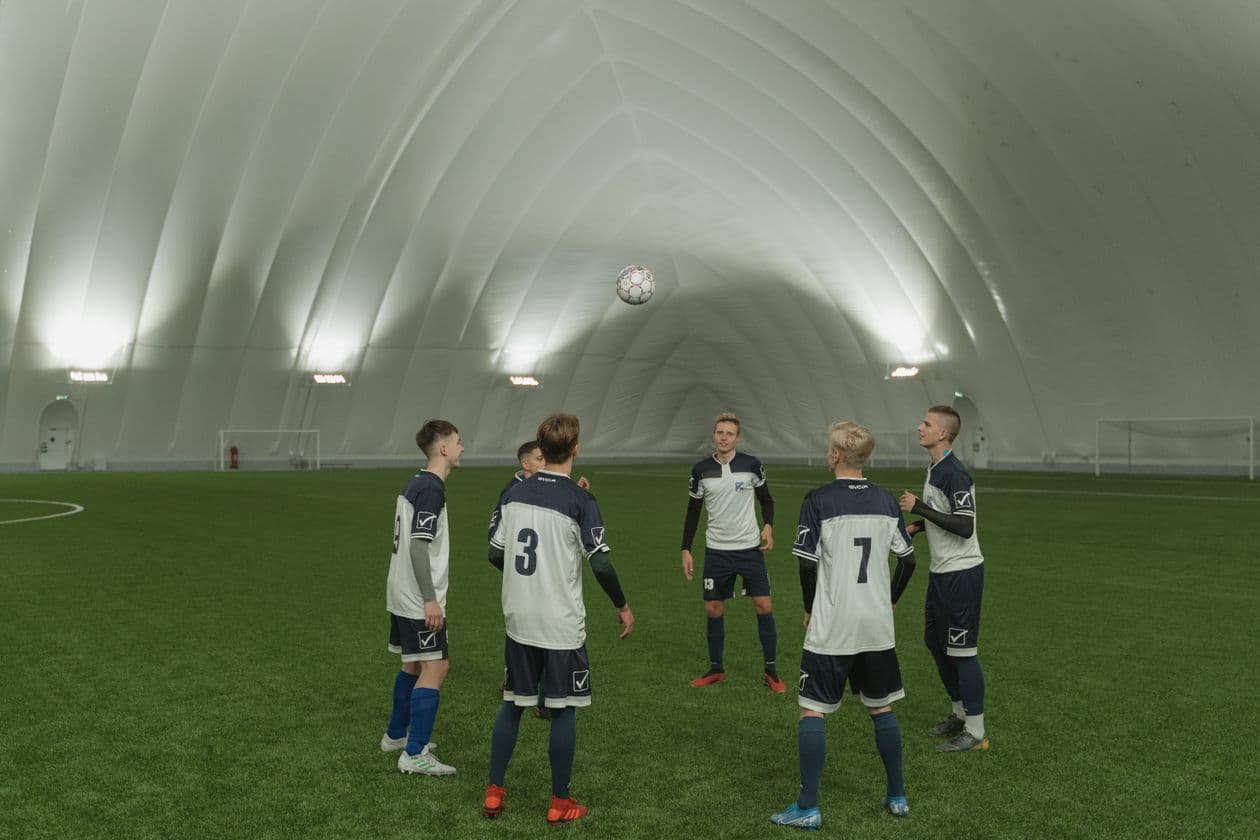 Soccer team in blue and white uniforms practicing together on indoor artificial turf during a training session