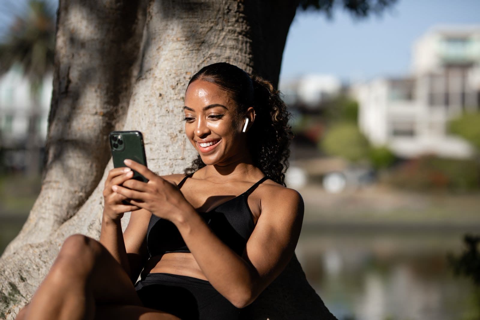 Person smiling while looking at their phone outdoors