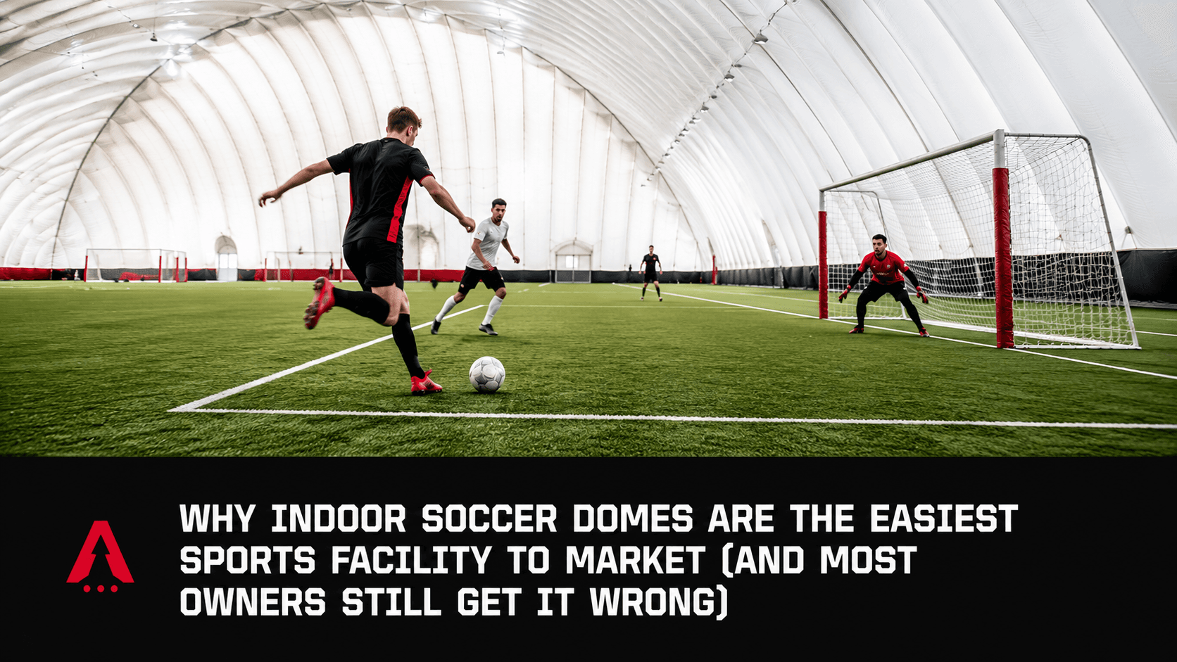 Player about to shoot on goal inside an indoor soccer dome with white inflatable roof and red goal posts
