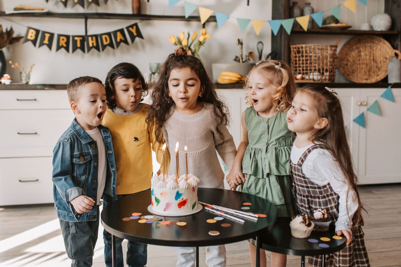 Group of children celebrating with birthday candles at an indoor family entertainment party