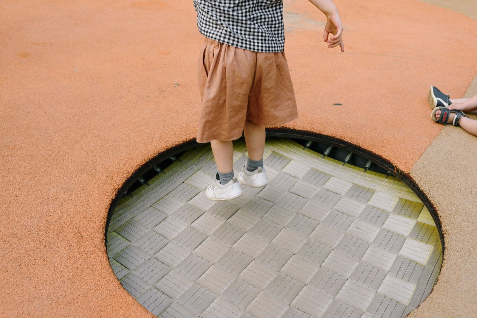 Person jumping high on a trampoline against a clear blue sky