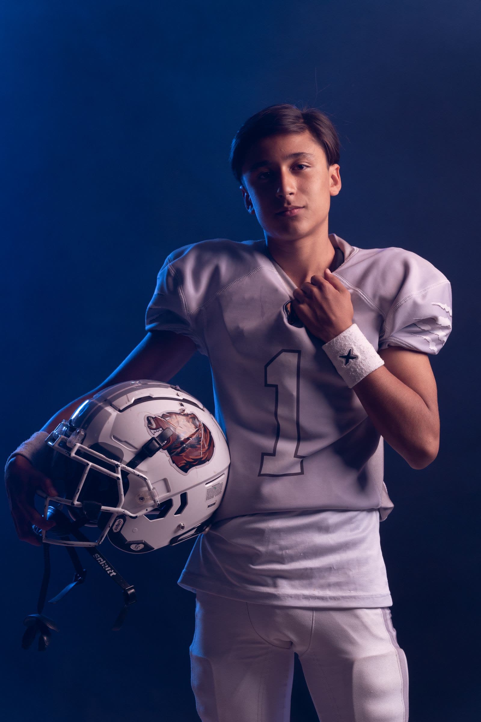Young football player in uniform holding his helmet