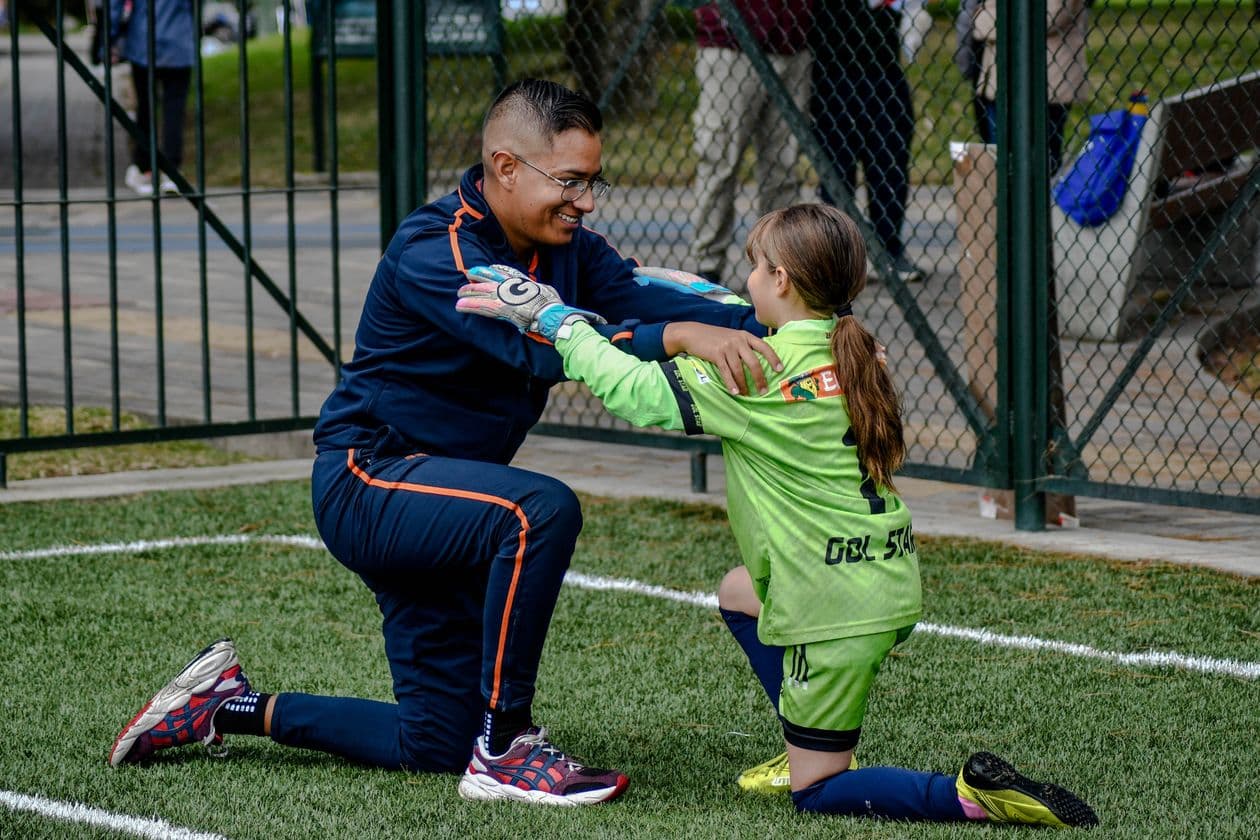 Coach encouraging a young soccer player on the sideline