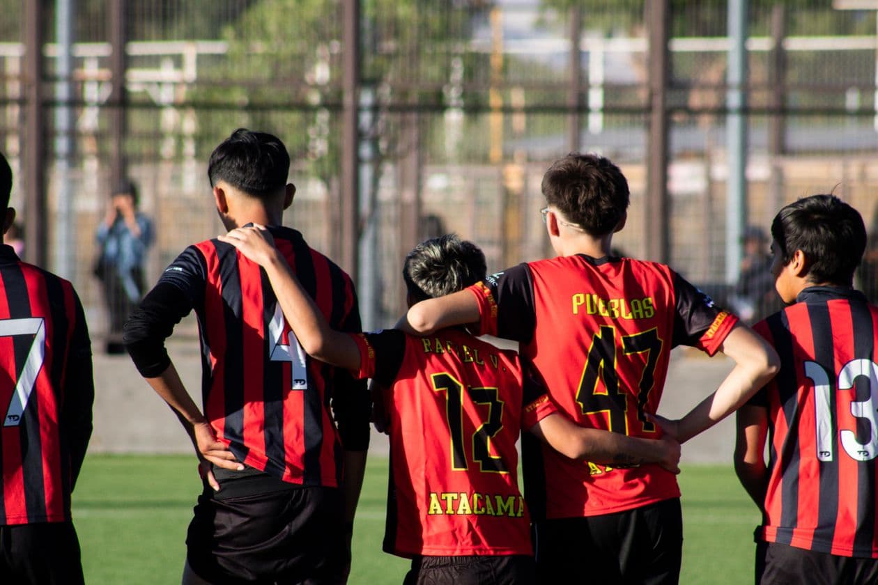 Youth soccer team huddling in numbered red and black jerseys
