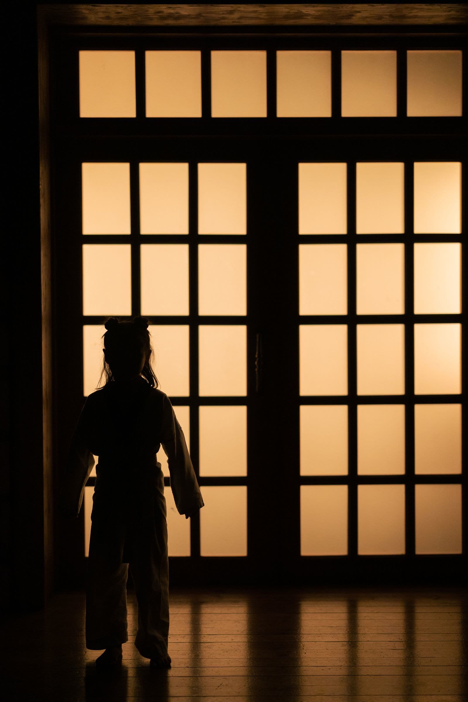 Silhouette of a child in training uniform standing indoors